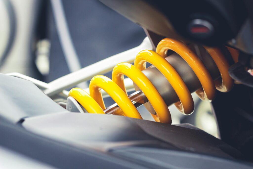 Close-up of a car's front suspension system with visible coil spring and shock absorber.